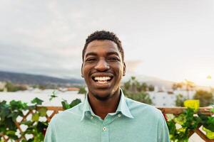 Happy young African man having fun smiling in front of camera on house patio photo