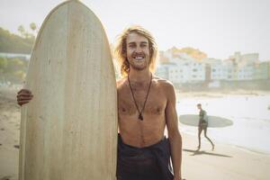 Young surfer having fun enjoying a surf day at sunset time - Extreme sport lifestyle people concept photo