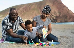 Happy African family having fun on the beach during summer holidays - Parents love concept photo