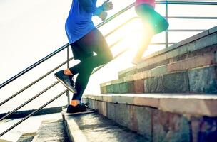 Couple running on stairs at sunset - Friends making a workout session exercising to get on staircase outdoor - Close up legs of people running - Sport, Health, lifestyle people concept photo