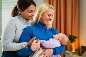 contento lesbiana Pareja teniendo oferta momentos con su pequeño bebé a hogar - familia y maternidad concepto foto