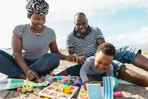 Happy African family having fun on the beach during summer holidays - Parents love concept photo