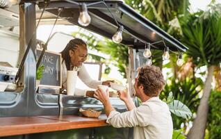 Afro food truck owner serving meal to male customer - Modern business and take away concept photo