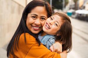 contento Sureste asiático madre con su hija teniendo divertido en el ciudad centrar - encantador familia al aire libre foto