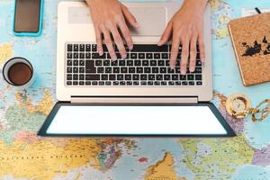 Top view female hands using laptop on world map booking next travel destinations - Young trip agent woman browsing online - Future traveling and technology concept photo