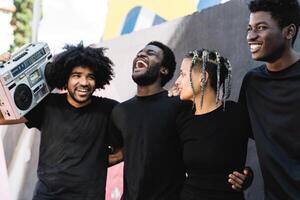 contento grupo de multirracial personas teniendo divertido escuchando música con Clásico boombox al aire libre - urbano calle personas estilo de vida foto