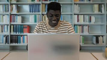 Young African student using laptop in library - School education concept photo