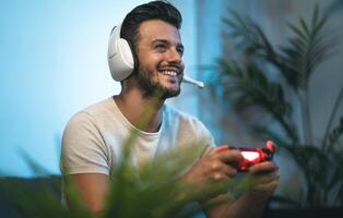 Young man playing online video games at home - Youth people addicted to new technology gaming entertainment photo