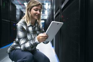 Female data center technician working inside server rack room photo