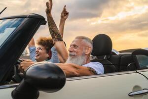 Happy senior couple having fun driving on new convertible car - Mature people enjoying time together during road trip tour vacation - Travel people lifestyle concept photo