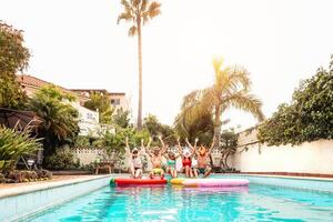 grupo contento amigos vistiendo máscara haciendo piscina fiesta - joven personas teniendo divertido celebrando evento en exclusivo nadando piscina verano tropical vacaciones - amistad y juventud Días festivos estilo de vida concepto foto