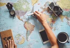 Top view of young woman planning her vacation using world map - Travel  influencer looking for the next travel destination - Concept of adventure, tourism, and traveling people lifestyle photo