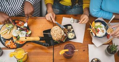 Top view of multiracial friends having healthy lunch in coffee brunch bar - Young people lifestyle and food nutrition concept photo