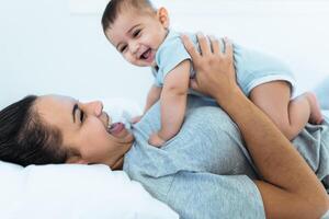 Happy mother lying on bed with her little baby - Family and Maternity concept photo