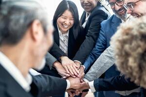 Multiracial business people stacking hands together in modern office - Teamwork concept photo