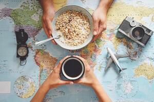 Top view of young couple planning next travel destination while drinking coffee and eating cereals - Concept of food and drink with tourism and traveling people lifestyle photo