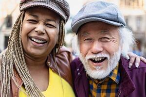 Happy multiracial senior couple having fun in city - Elderly people and love relationship concept photo