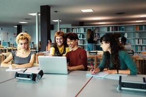 Young university students using laptop and studying with books in library - School education concept photo