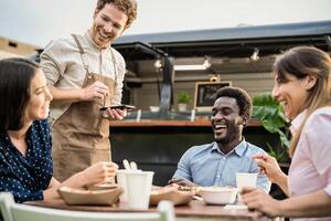 comida camión propietario tomando clientes pedidos con móvil dispositivo - contento multirracial personas teniendo un comida al aire libre foto