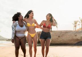 Happy multiracial females with different body size having fun on the beach during summer holidays photo