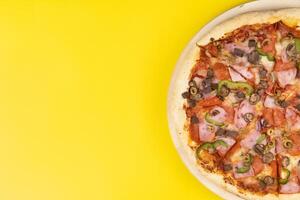 Delicious large pizza with veal and mushrooms on a yellow background photo