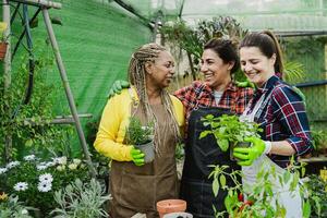 Happy multiracial women working together in plants and flowers garden shop photo