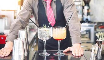 Young bartender making cocktails at bar counter - Barman serving drinks - Work, passion and mixologist concept photo