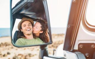 contento Pareja teniendo un oferta momento durante su la carretera viaje con un convertible coche - pov en un coche espejo de joven viaje personas en su vacaciones - amar, relación, viajero estilo de vida concepto foto