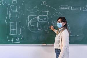 hembra profesor dando lección a estudiantes en alto colegio durante corona virus pandemia - educación concepto foto