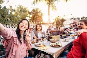 contento familia aplausos y tostado con rojo vino lentes a cena al aire libre - personas con diferente siglos y etnia teniendo divertido a barbacoa fiesta - comida y beber, retirado y joven personas concepto foto