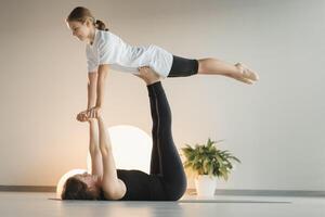 Mom and teenage daughter do gymnastics together in the fitness room. A woman and a girl train in the gym photo