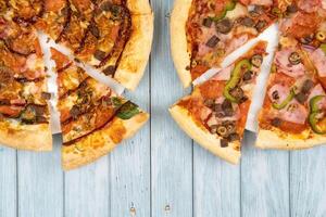 Two different delicious big pizzas on a blue wooden background photo