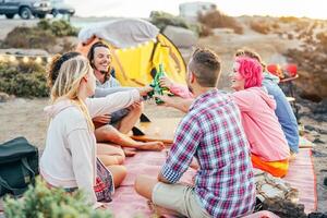 contento amigos tostado con cervezas a parilla cena en el playa - joven personas cámping con tienda teniendo divertido aplausos y Bebiendo cerveza - amistad y juventud estilo de vida vacaciones concepto foto