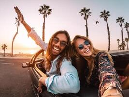 Happy young couple doing road trip in tropical city - Travel trendy people having fun driving in convertible car discovering new places - Relationship and youth vacation lifestyle concept photo