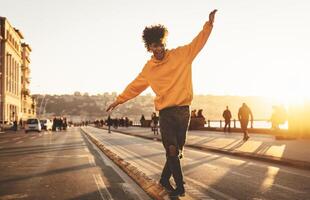 Afro American man having fun walking in city center - Happy young guy enjoying time a sunset outdoor - Millennial generation lifestyle and positive people attitude concept photo