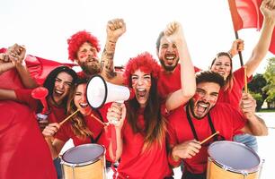 Football fans watching soccer match event at stadium - Young people having fun supporting favorite club - Sport entertainment concept photo