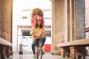 contento Pareja yendo en bicicleta en el ciudad centrar - joven personas teniendo divertido al aire libre - milenario Generacion y juventud estilo de vida concepto foto
