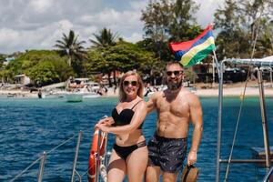 Smiling young couple looking at each other, standing on board the yacht. photo