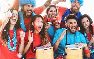 Football fans watching soccer match event at stadium - Young people having fun supporting favorite club - Sport entertainment concept photo