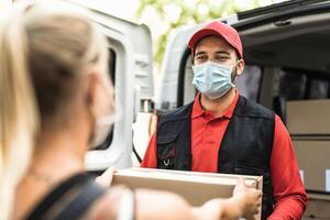 Delivery man at work wearing face  mask - Young woman receiving an online order from courier express photo