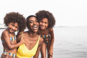 Happy African family on the beach during summer holidays - Afro American people having fun on vacation time - Parents love and travel lifestyle concept photo