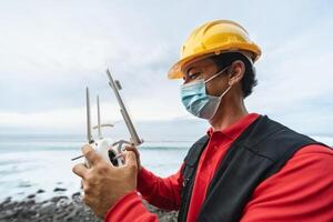 Male engineer monitoring the drone inspection while wearing face mask to avoid corona virus spreading - Technology and industrial concept photo