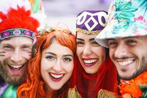 Happy friends celebrating carnival party outdoor - Portrait young crazy people having fun wearing funny costumes - Youth holidays culture lifestyle concept photo