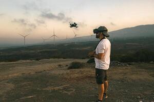 Drone engineer using first person view technology on the turbine farm - Alternative energy and aerial engineering concept photo
