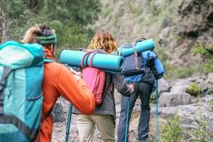 Group of people with backpacks doing trekking excursion on mountain - Young  tourists walking and exploring the nature - Trekker, hike and travel concept photo