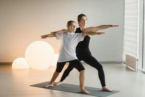 Mom and teenage daughter do gymnastics together in the fitness room. A woman and a girl train in the gym photo