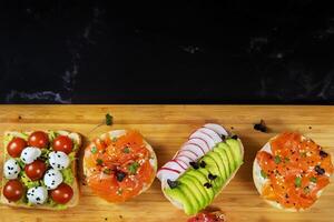Assorted sandwiches with fish, cheese, meat and vegetables lying on the board photo