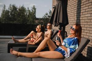 un contento familia en trajes de baño tomar el sol en verano en su terraza en Dom camas foto