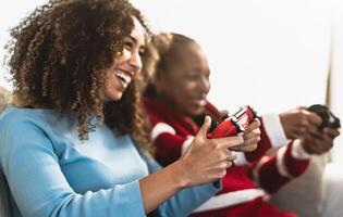 Happy African mother and daughter having fun playing online video games at home - Gaming entertainment and technology concept photo