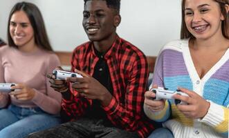 joven multirracial adolescentes jugando en línea vídeo juego consola a hogar - juventud personas fanático a nuevo tecnología juego de azar entretenimiento foto